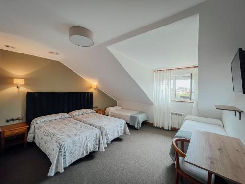 a hotel room with two beds and a table at Hotel San Jorge in Nueva de Llanes