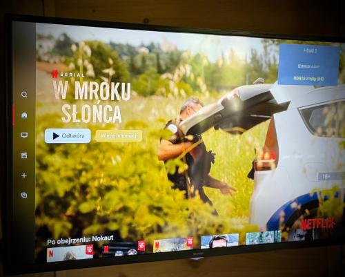 a television screen with a picture of a man holding an umbrella at SeaUSasino - Luksusowe Drewniane Domy z Kominkami in Sasino