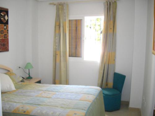 a bedroom with a bed and a chair and a window at Residencial Veramar 4, Vera Playa, Almeria in Vera