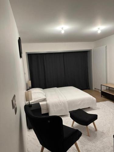 een slaapkamer met een wit bed en een zwarte stoel bij Cosy Parisian Upscale Apartment in Parijs