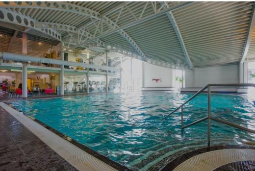 a large swimming pool with blue water in a building at 10 Borwick Lakes, Carnforth - En suite - King size bed in Carnforth
