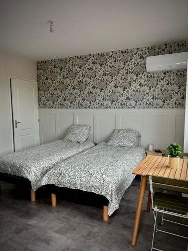 a bedroom with two beds and a wooden table at L'Escale de la Râperie, logement 3 in Tincourt-Boucly