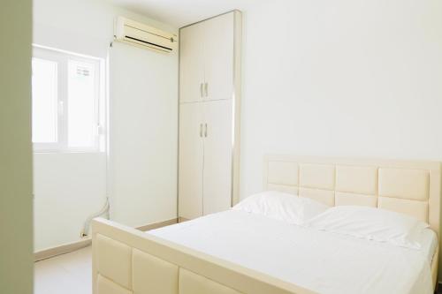 a white bedroom with a bed and a mirror at Sunny View Apartment in Sarandë