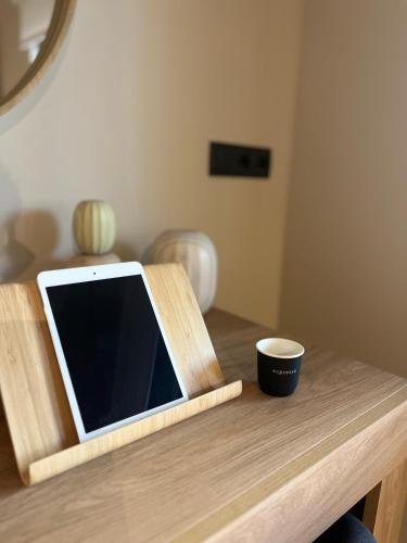 a tablet on a wooden table with a cup on it at Χenion Inn - Athens Airport, Easy Check In Anytime in Markopoulo