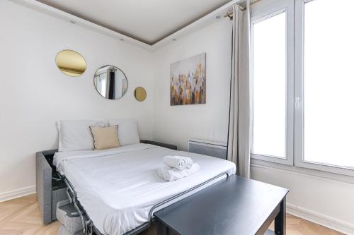 une petite chambre avec un lit et une table dans l'établissement So Ouest Courcelles Magnifique Studio, à Levallois-Perret