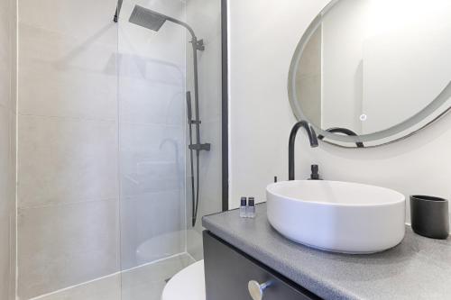 une salle de bain blanche avec un lavabo et une douche dans l'établissement So Ouest Courcelles Magnifique Studio, à Levallois-Perret