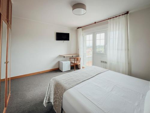 a bedroom with a bed and a table and a window at Hotel San Jorge in Nueva de Llanes