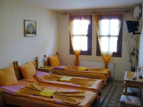 a group of three beds in a room with windows at Family Hotel Varusha in Veliko Tŭrnovo