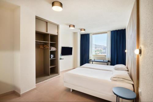 a bedroom with a large white bed and a window at Hesperia Sant Joan in Sant Joan Despí