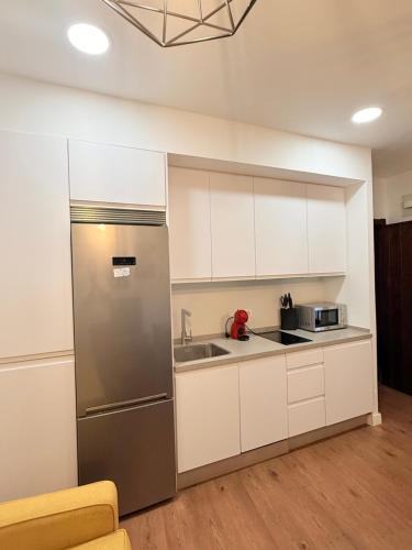 a kitchen with white cabinets and a stainless steel refrigerator at Apartamentos Molinos in Constantina