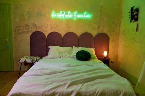 a bedroom with a bed with a neon sign on the wall at Alma ART B&B in Dobrovo