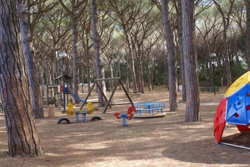 a park with several playground equipment and trees at Golfo di Maremma Village in Albinia