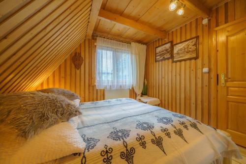 a bedroom with a bed in a room with wooden walls at Chata Aleksandra in Zakopane