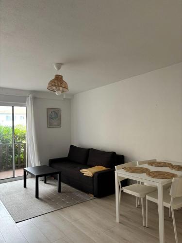un salon avec un canapé noir et une table dans l'établissement CAPUCINES - T2 ANGLET avec stationnement, à Anglet