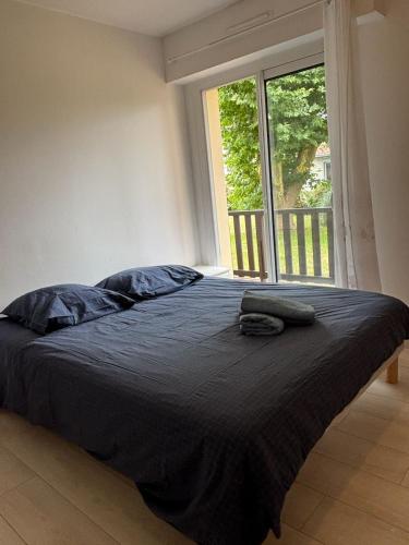 un lit dans une chambre avec une grande fenêtre dans l'établissement CAPUCINES - T2 ANGLET avec stationnement, à Anglet