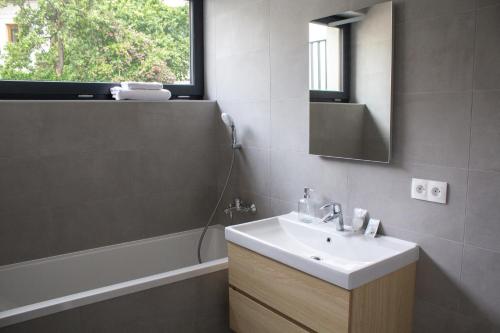 a bathroom with a sink and a mirror and a tub at Hotel Taxis Bratislava - Suites in Bratislava