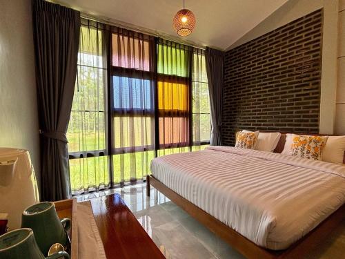 a bedroom with a large bed and large windows at Moonlight Cottage in Ban Pa Khlok