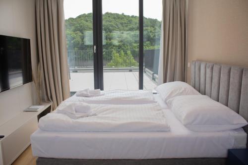 a white bed in a room with a large window at Hotel Taxis Bratislava - Suites in Bratislava