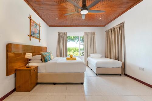 Grand'Anse PraslinにあるOcean Villaのベッド2台と天井ファン付きの寝室