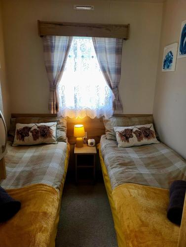 two beds in a small room with a window at 61 St Andrew's 3 bedroom Cozy Caravan near Edinburgh Seton Sands Holiday Village in Port Seton