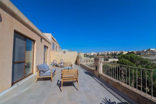 a balcony with two chairs and a table on a building at Penthouse with Xlendi Views & Two large Terraces in Munxar