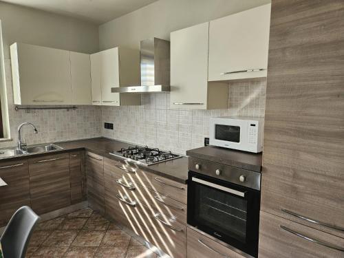 a kitchen with white cabinets and a stove and a microwave at A casa di Thelma in Barolo