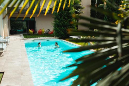 two children swimming in a swimming pool at Logis Hôtel Victor Hugo & Spa in Besançon