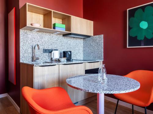 una cucina con tavolo e 2 sedie arancioni di Numa Berlin Friedrichshain a Berlino