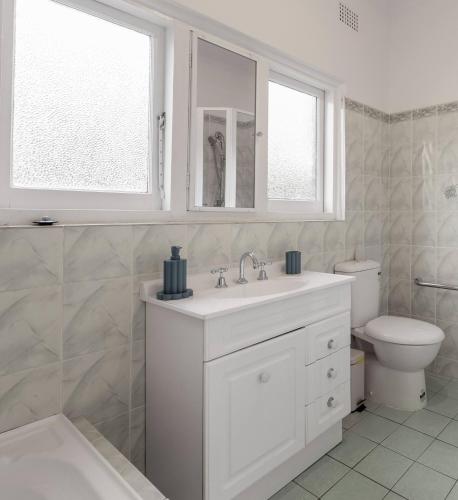a white bathroom with a sink and a toilet at Ideal Location, 4 Beds, Mid-Century Home in Orange