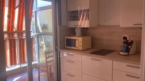 une cuisine avec un four micro-ondes sur un comptoir à côté d'une fenêtre dans l'établissement Grand Studio Nice proche plages et Promenade des Anglais, à Nice