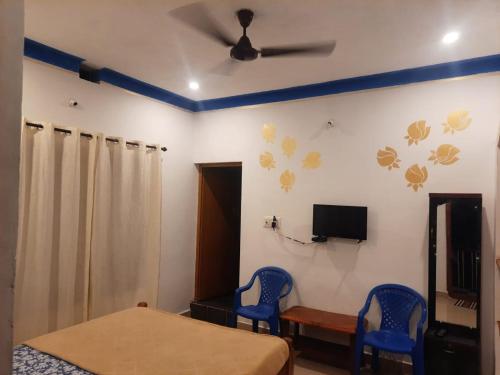 Un dormitorio con dos sillas azules y un ventilador de techo. en Coorg Relax Home, en Madikeri