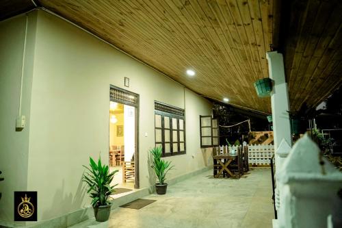 a white building with potted plants and a wooden ceiling at Ravana Guest House in Nilaveli