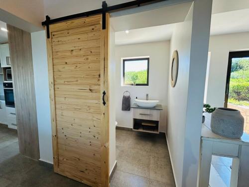 a bathroom with a wooden door and a sink at Bayview Bliss at Springerbaai in Mossel Bay