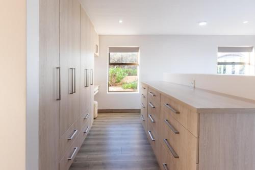 a kitchen with white cabinets and a wooden floor at Bayview Bliss at Springerbaai in Mossel Bay