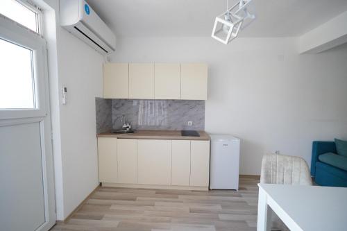 a small kitchen with white cabinets and a blue couch at Le Nina Apartments - Deluxe and Studio in Strumica