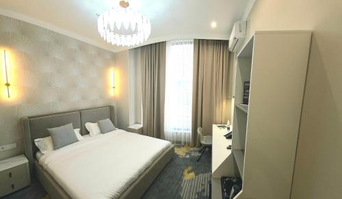 a bedroom with a white bed and a chandelier at Palmira Hotel Bishkek in Bishkek