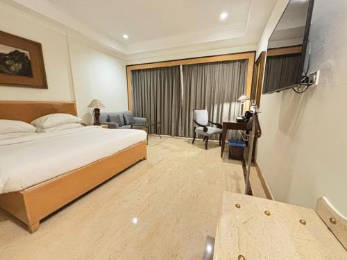 ein Hotelzimmer mit einem Bett, einem Schreibtisch und einem Fenster in der Unterkunft The Hans, New Delhi in Neu-Delhi