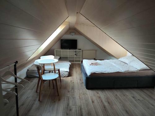 a attic bedroom with a bed and a table and chairs at Willa IDYLLA in Kołobrzeg
