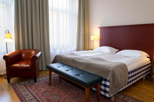 a bedroom with a large bed with a chair and a chair at Hotel Bishops Arms Köping in Köping