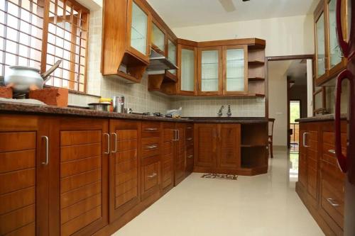 a large kitchen with wooden cabinets and a sink at Casa Perla by Eco Escape Hub in Trivandrum