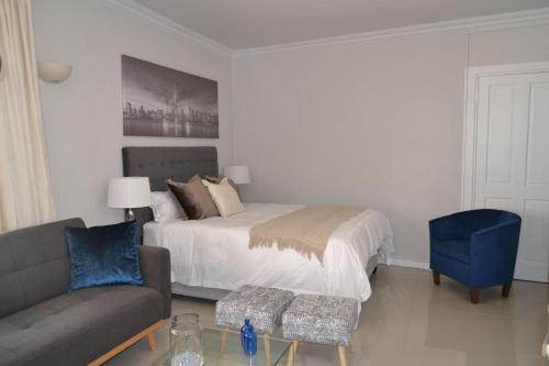 Un dormitorio con una cama, un sofá y una silla. en 7 Woodmead Suites, en Johannesburgo