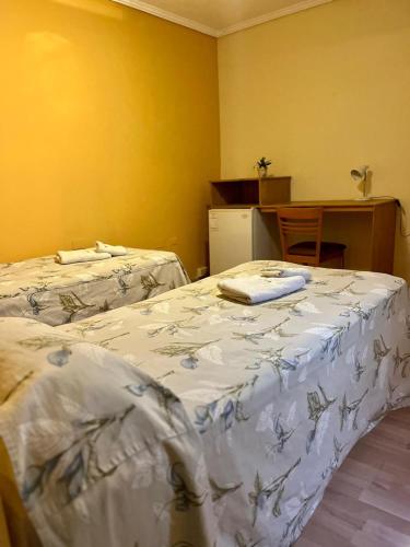 a room with two beds and a table with a desk at HOTEL LOS TILOS RECONQUISTA in Reconquista