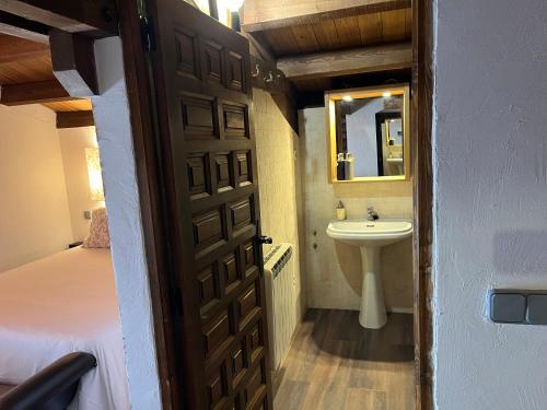 a bathroom with a bed and a sink and a door at El Horno in Irueste