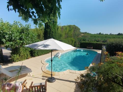 une piscine avec un parasol et un patio dans l'établissement La Chambre du Saunei, à Castelnau-de-Guers
