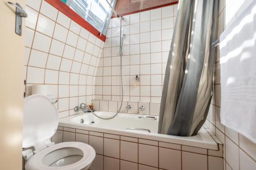 un baño con inodoro y bañera en Stratfords Guesthouse and Conference Venue, en East London