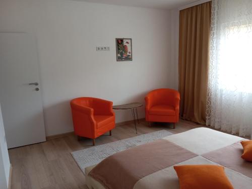 a bedroom with two orange chairs and a bed at Apartmani Mušinbegović in Visoko