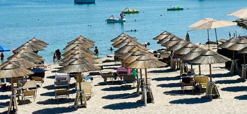 a beach with chairs and umbrellas and people in the water at Alloggio Ulivi in Isola Rossa
