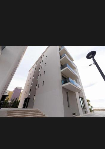 a tall white building with stairs and a street light at DeSa Radhime in Radhimë