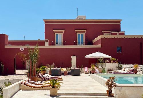 a red building with a swimming pool and a house at Antica Masseria le Monache in Grottaglie
