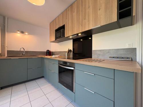 a large kitchen with blue cabinets and a sink at Nymphéas - Charming apartment village center in Saint-Martin-de-Bréthencourt